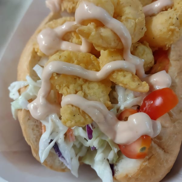 Cajun shrimp po'boy with fried shrimp, coleslaw, cherry tomatoes, and creamy sauce.